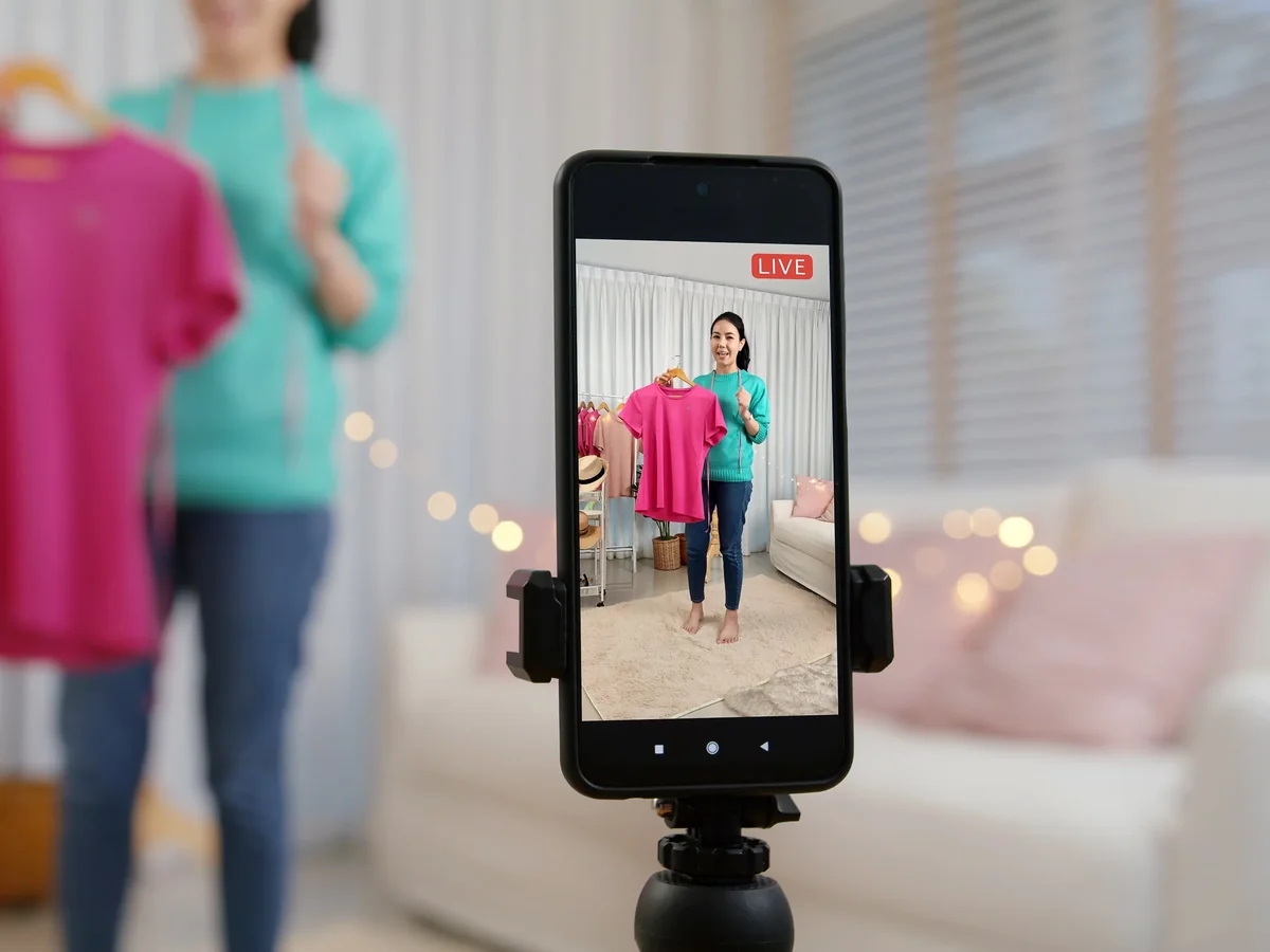 Celular em tripé transmitindo uma live de vendas, com o selo LIVE na tela